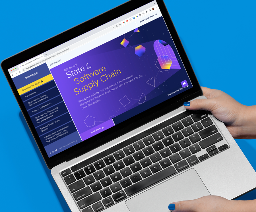 hands hold up a laptop screen showing the home screen of the State of the Software Supply chain report